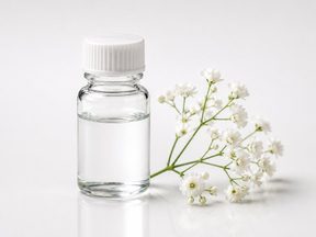 Clear liquid vial beside white blossom